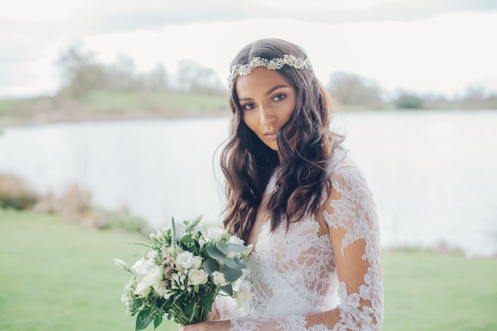 Bride looks to camera whilst holding bouquet