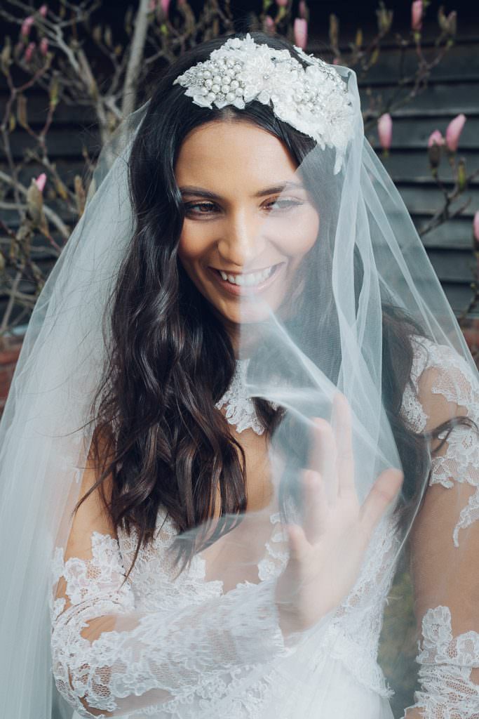 Bride laughing and smiling whilst playing with veil