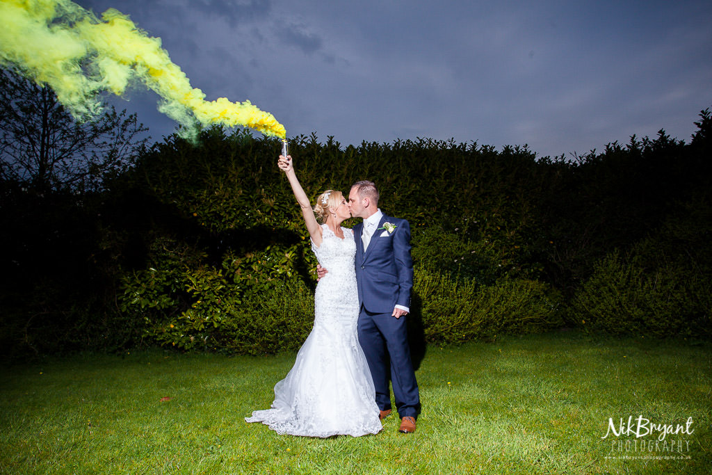 Bride and groom kiss with smoke grenade
