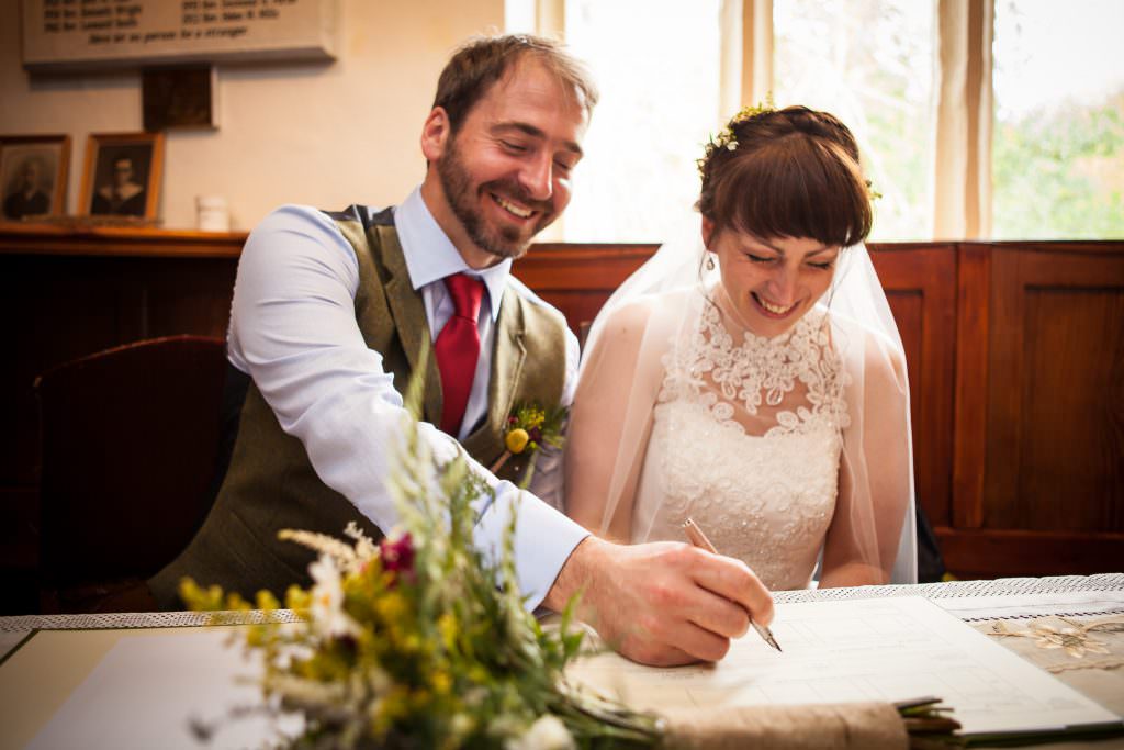 A couple laugh as they sign the wedding register
