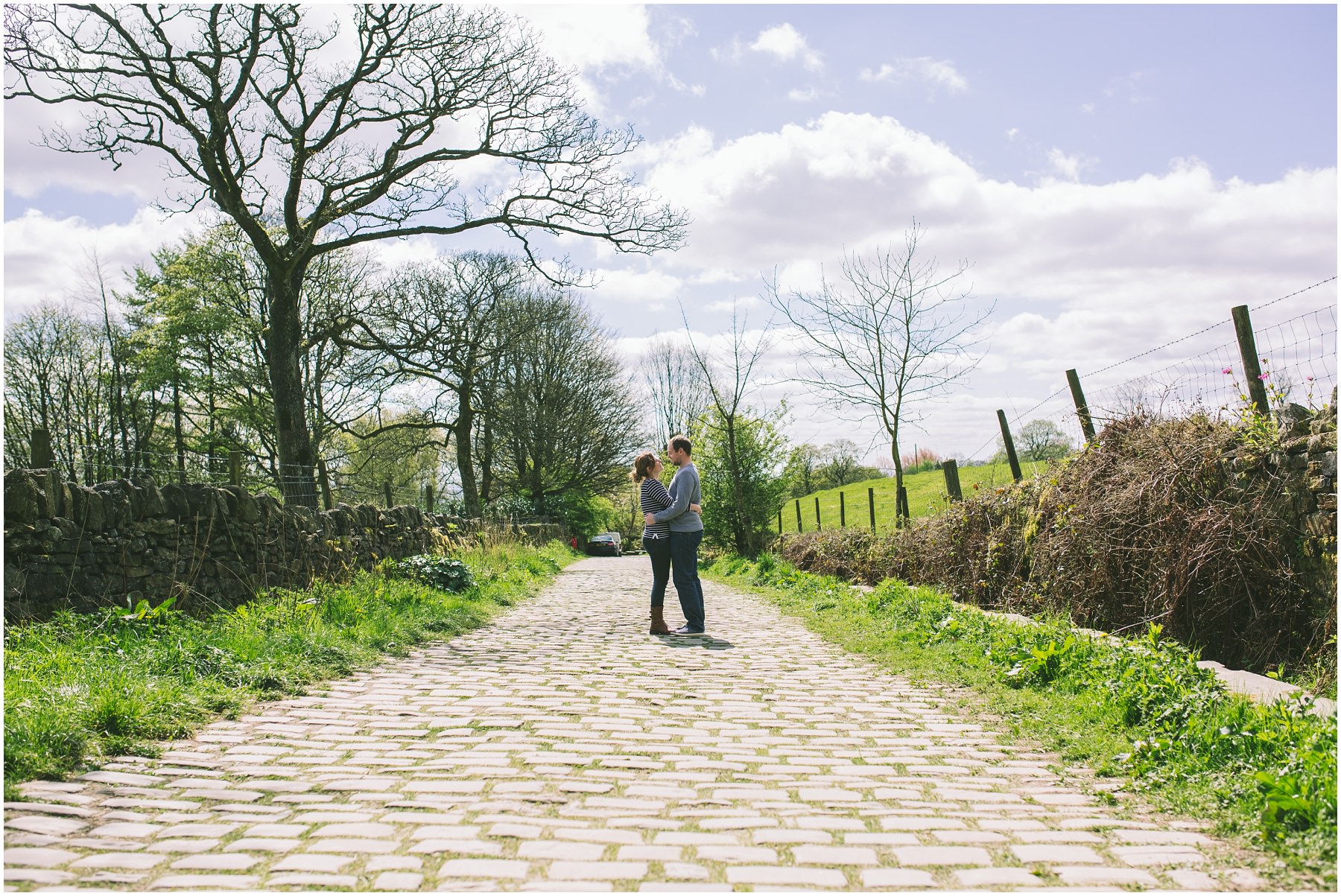 a couple stand on a cobbled lane and embrace