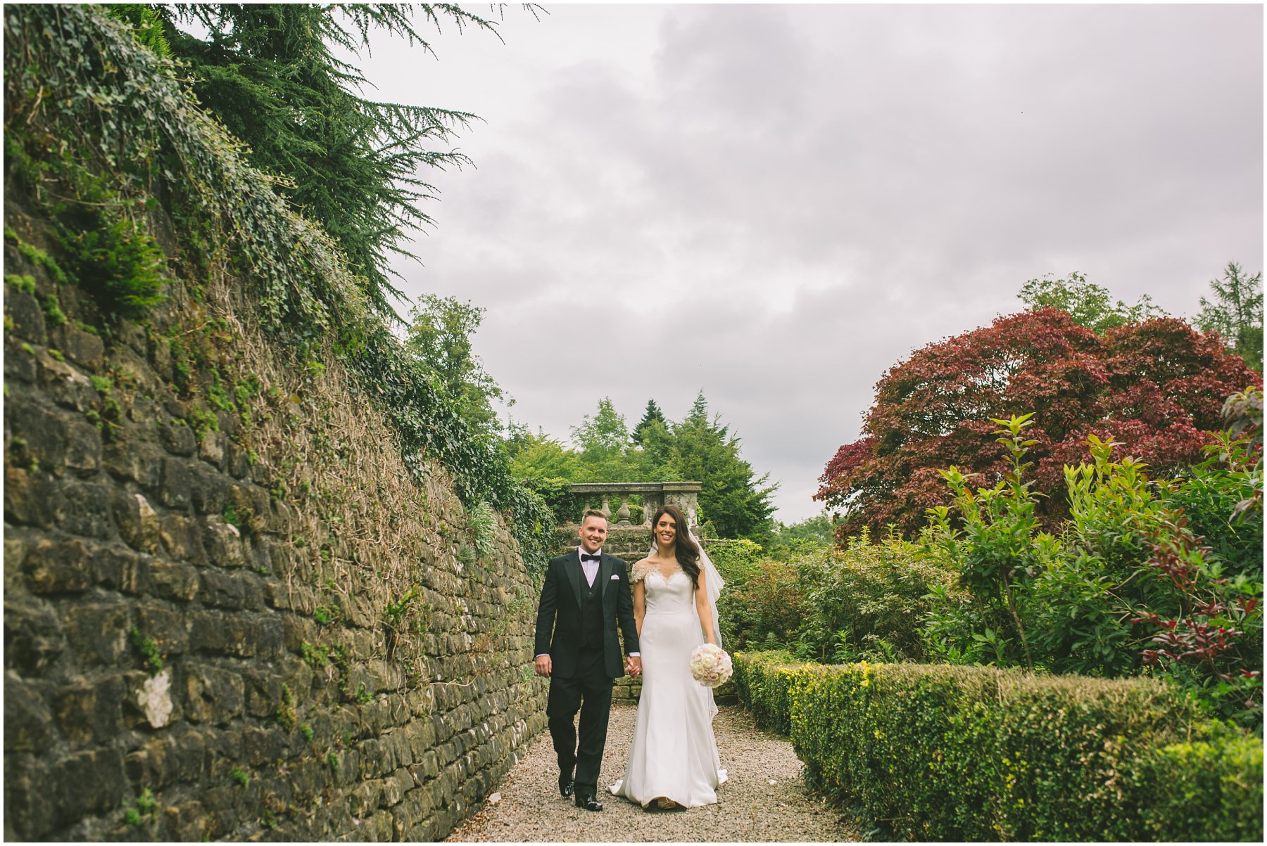 married couple walk through the gardens at Eaves Hall