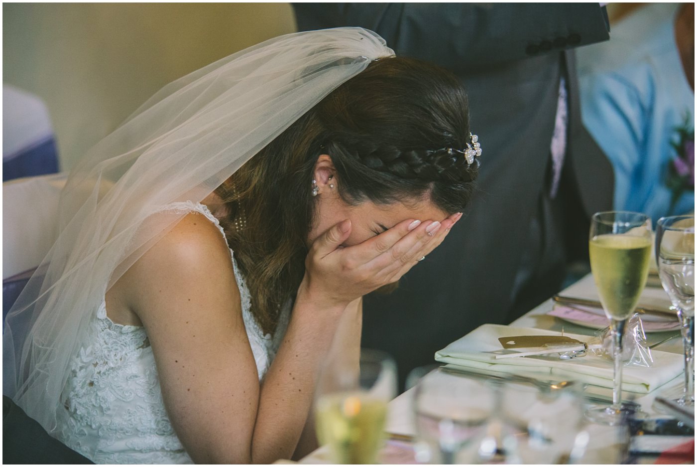 bride hides her face in her hands during an embarrassing speech by dad