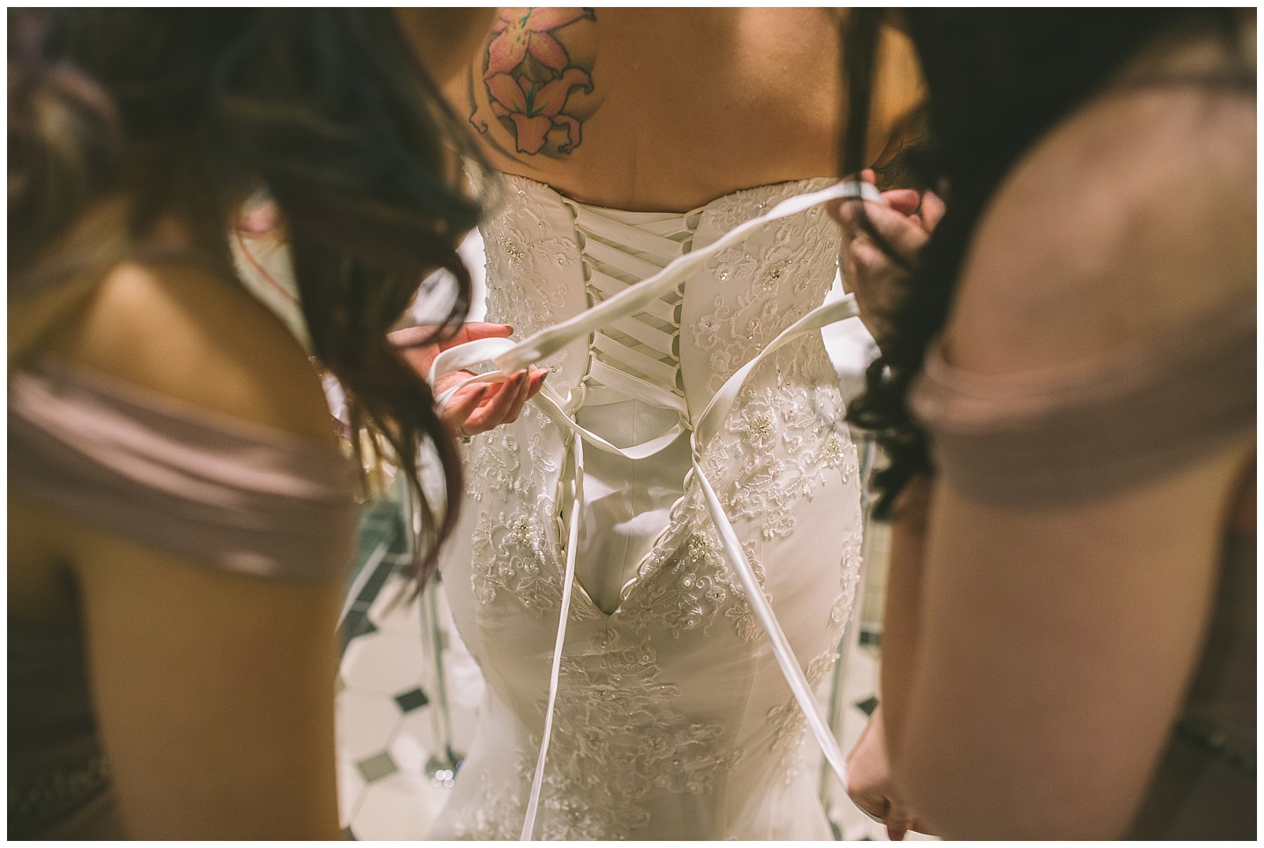wedding dress being laced up by bridesmaids