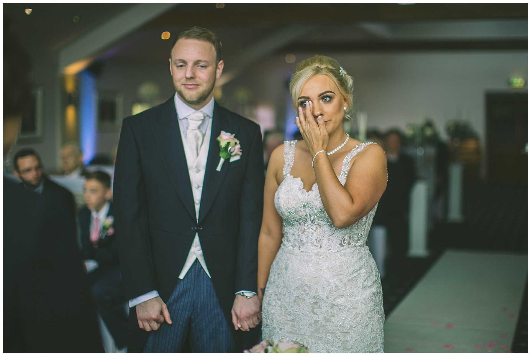 Bride wipes a tear from her eye during wedding ceremony
