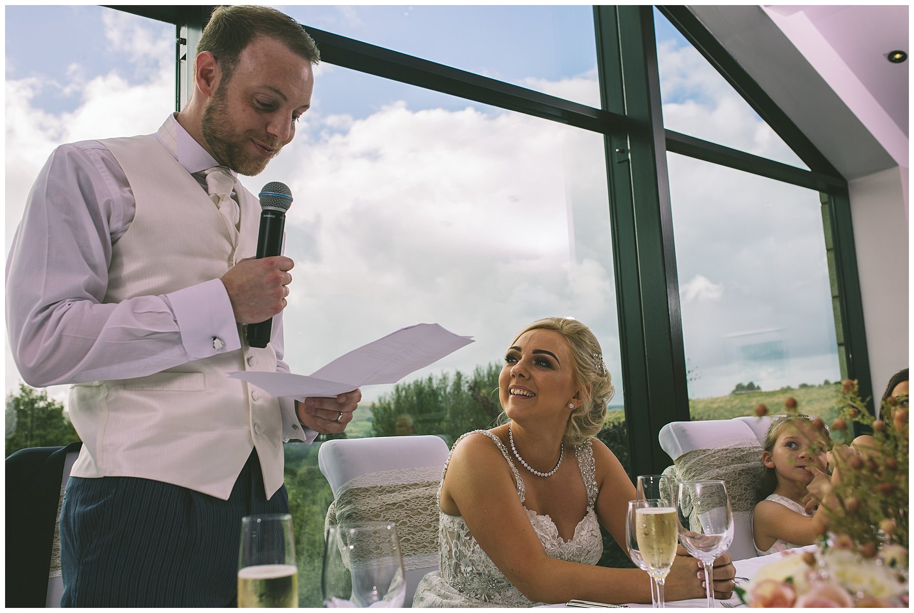 Bride looks at her new husband as he gives a speech