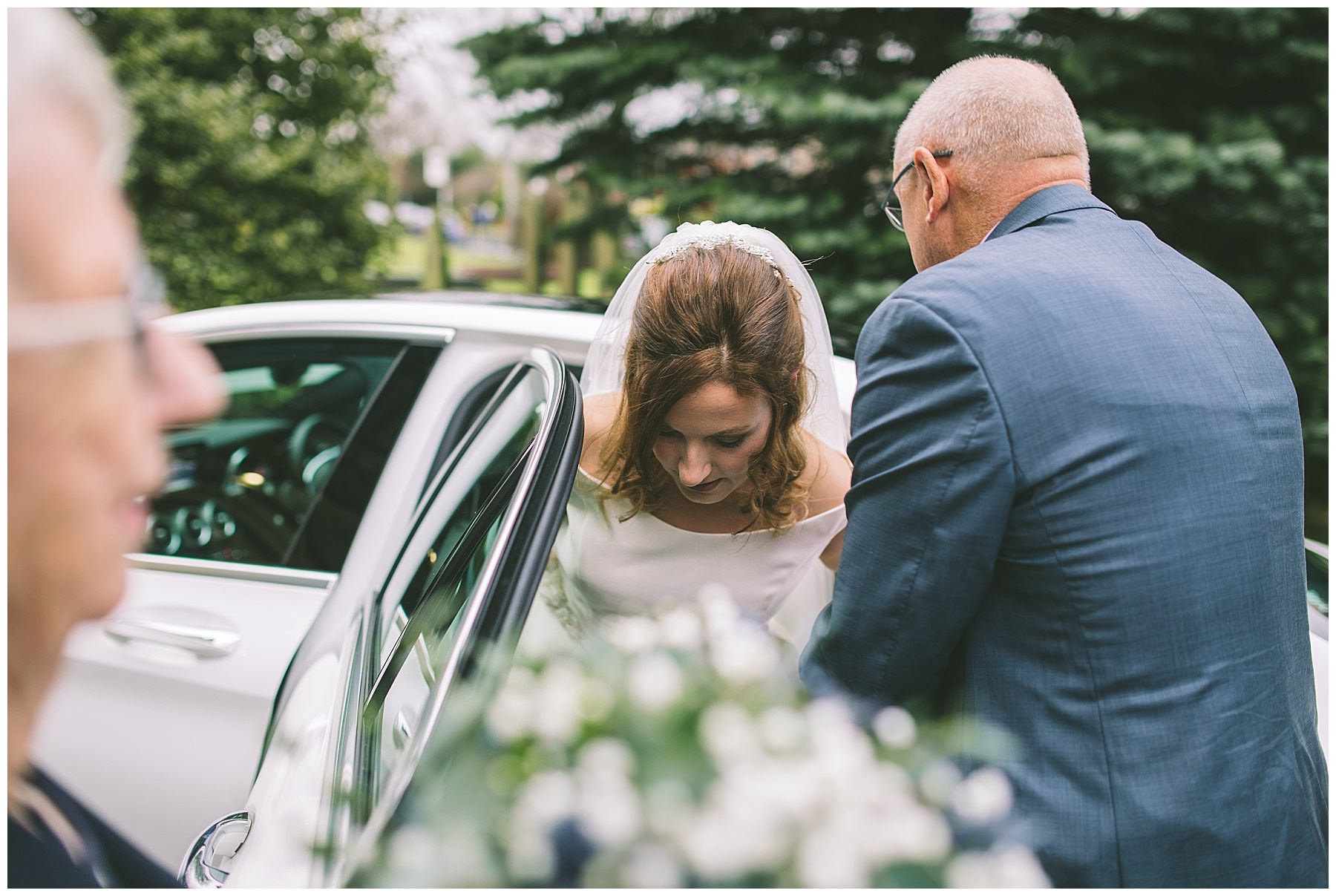 Brides dad helps her out of car as she arrives at church