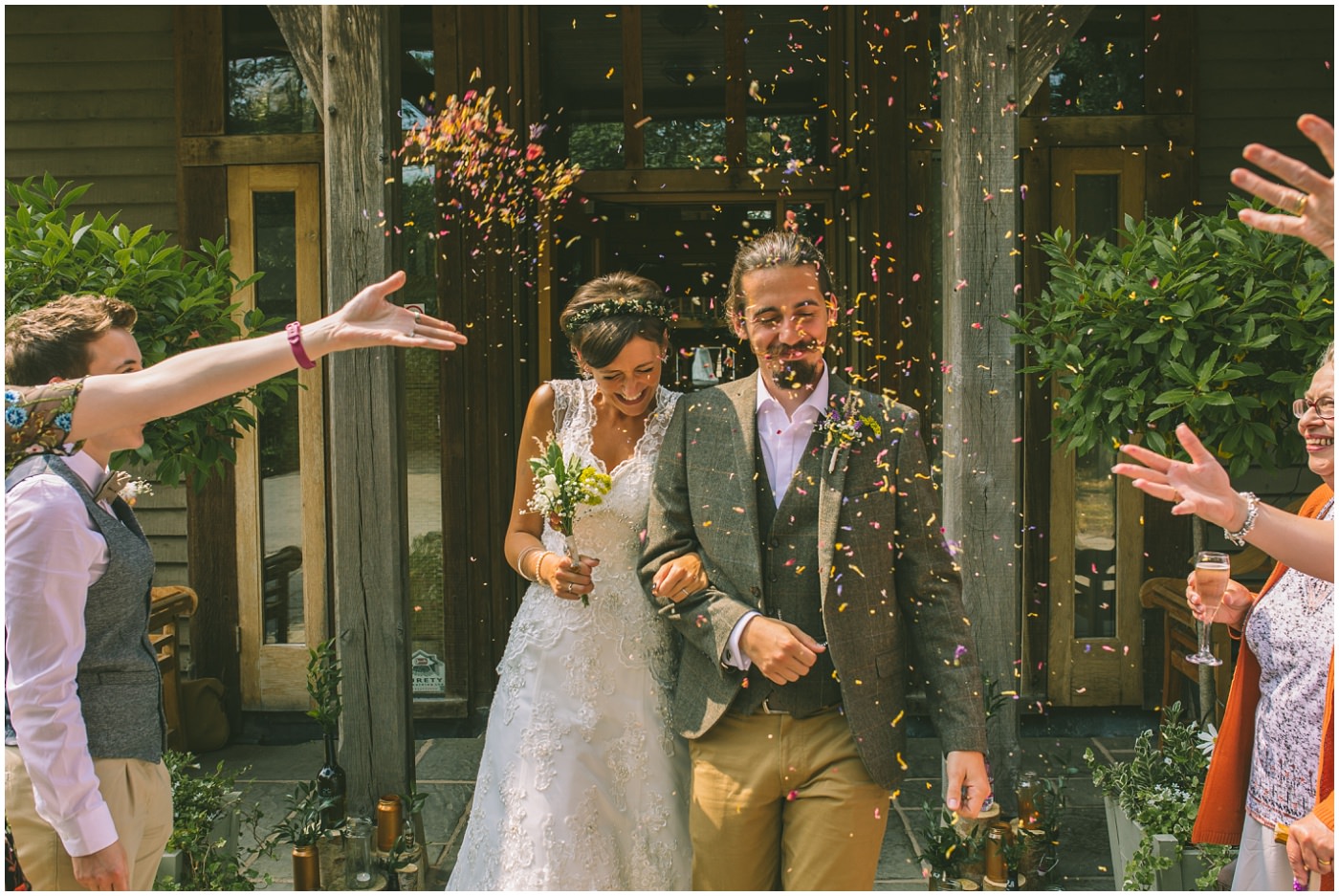 Bride and groom walk arm in arm through confetti