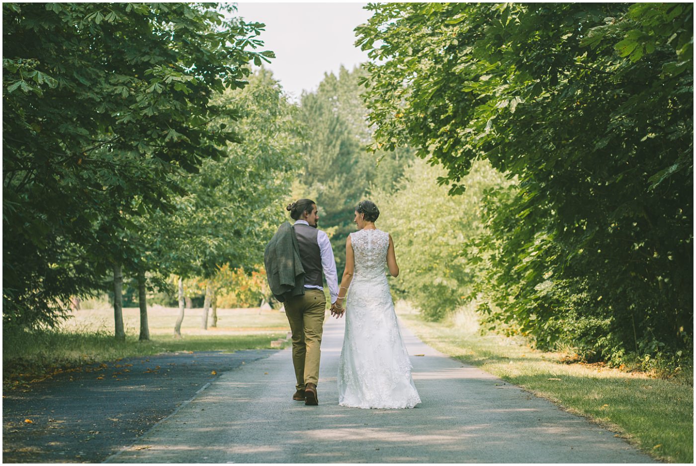 Bride and Groom walk hand in hand down the drive way of the oaktree of peover