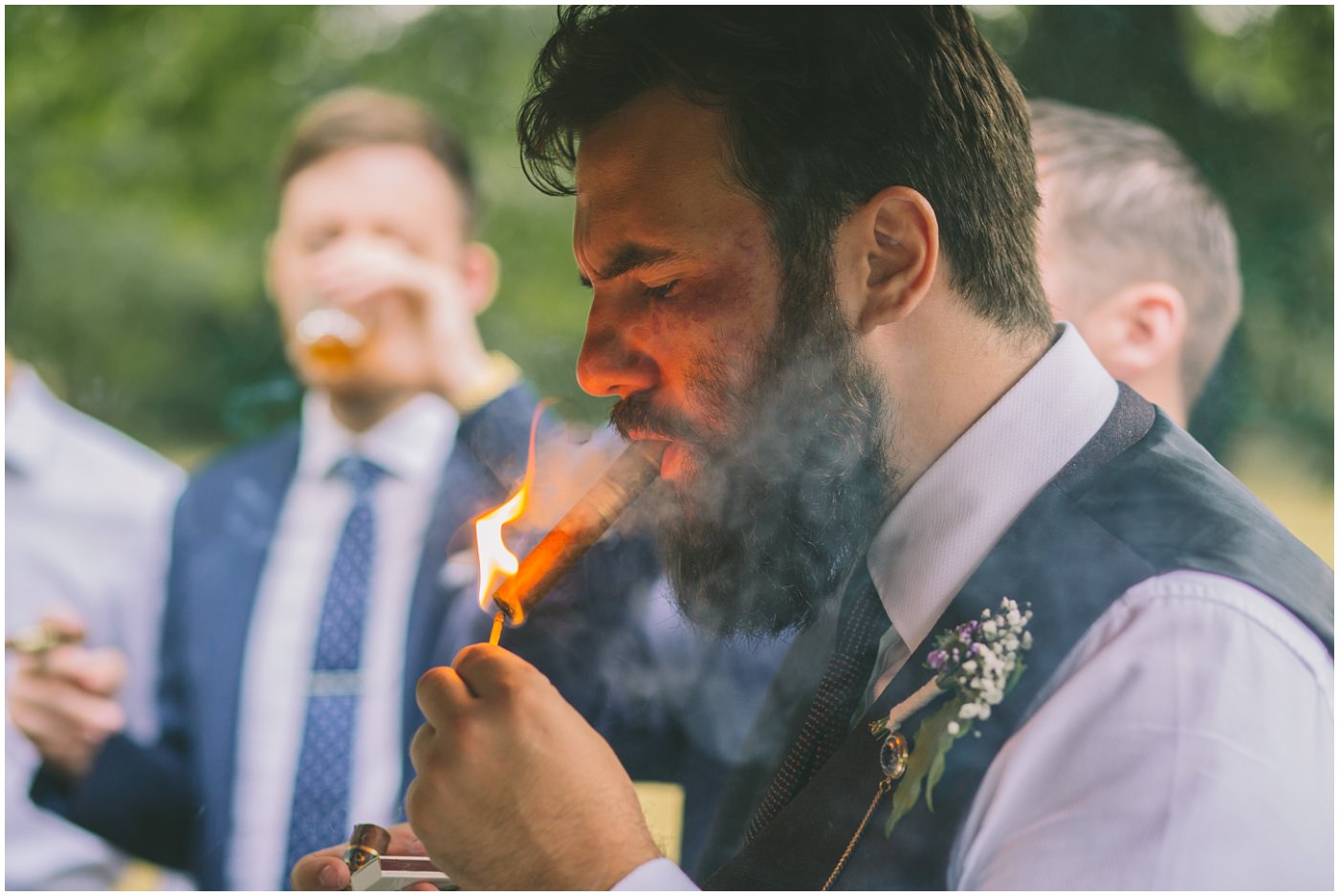 groomsman lights a cigar outside the venue