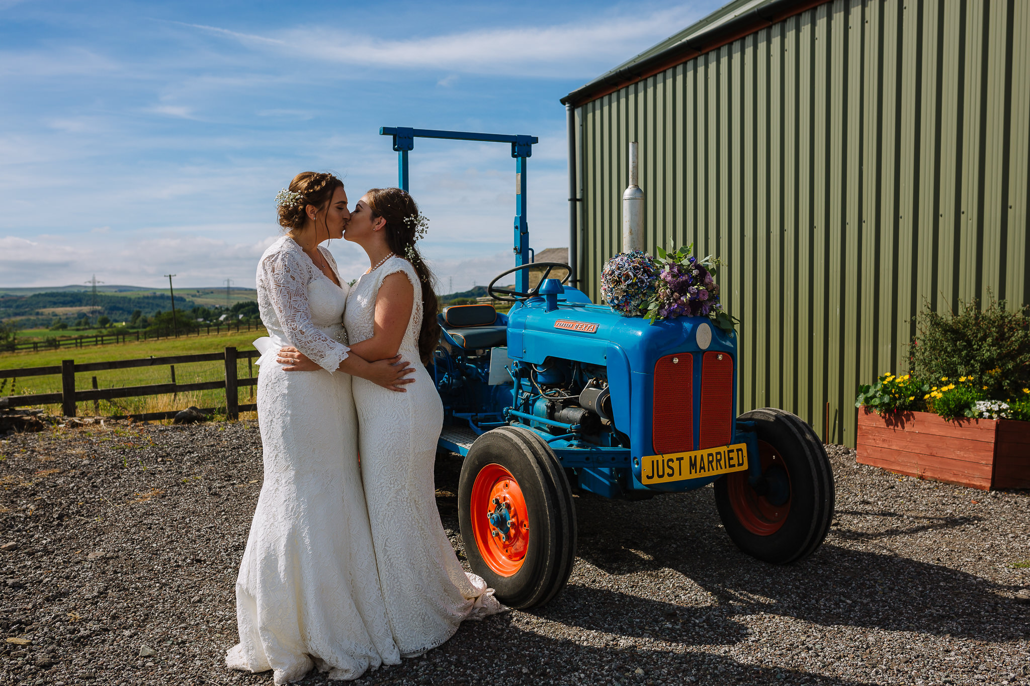 same sex couple kiss in front of the tractor at the wellbeing farm