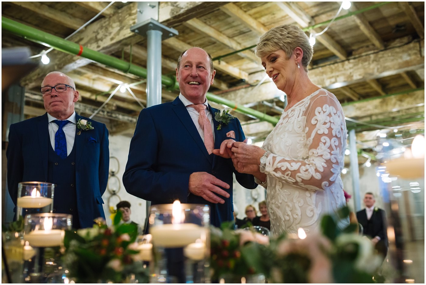 bride and groom smile as they exchange rings during wedding ceremony at holmes mill