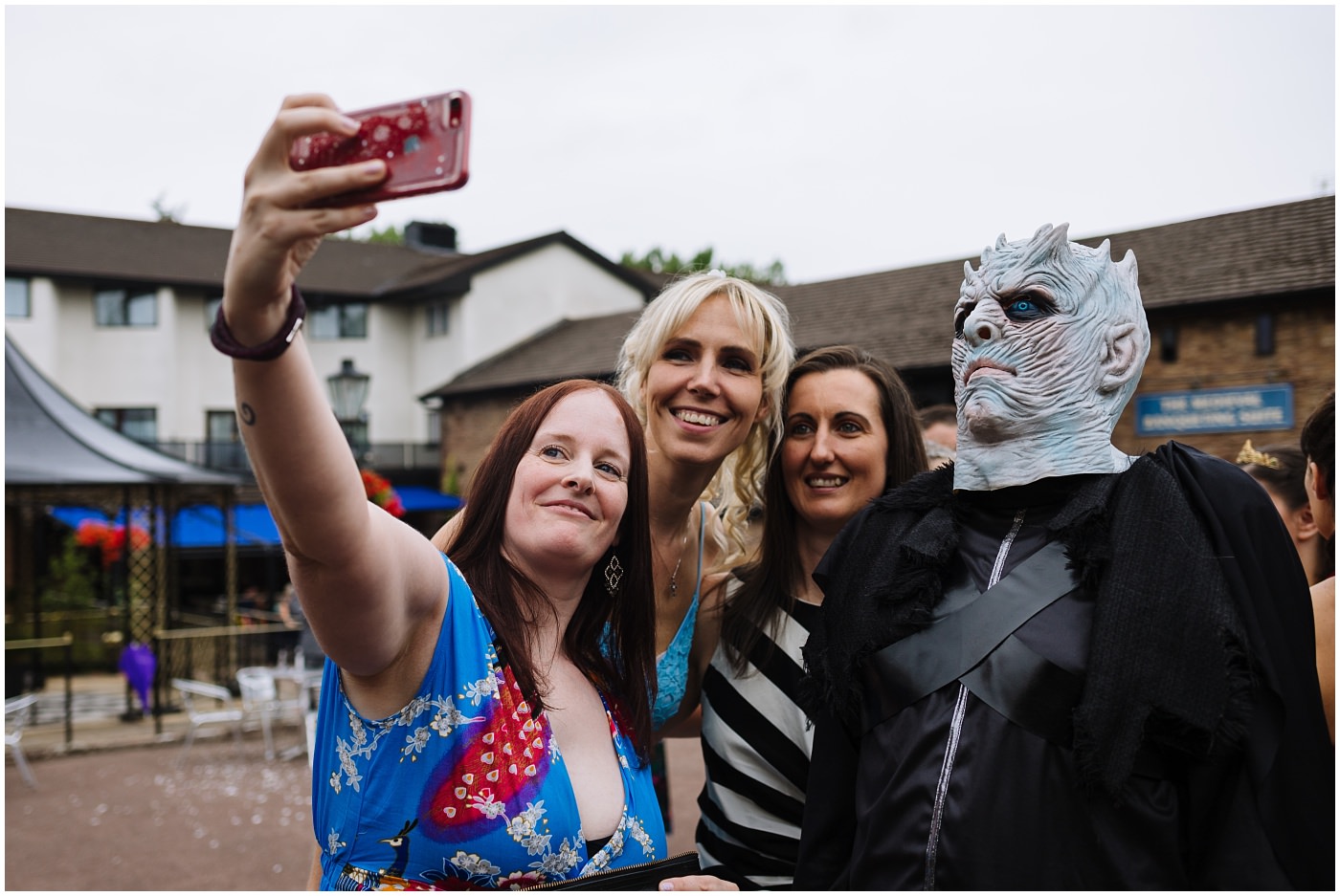 wedding guests take selfie with guest in fancy dress