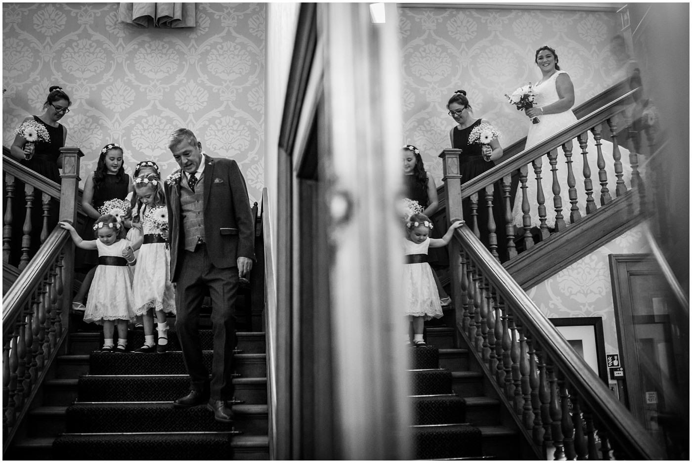 Father of the bride leads bridesmaids and bride downstairs