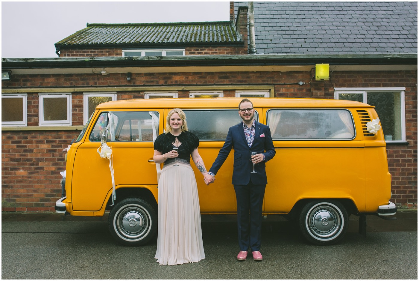 Couple stand holding hands in front of orange camper van