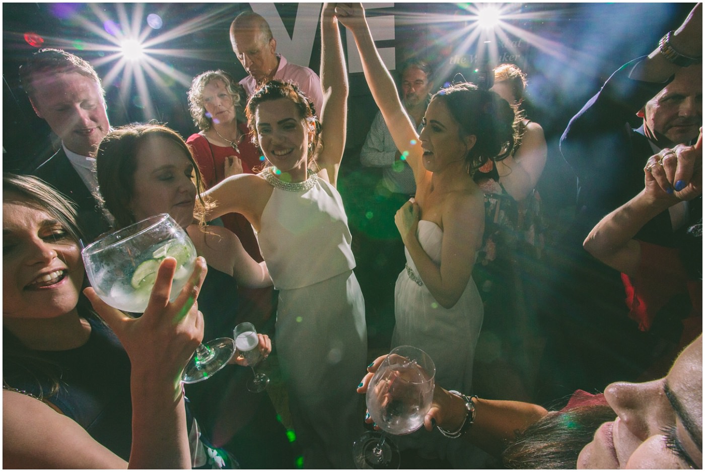 two brides dance surrounded by guests