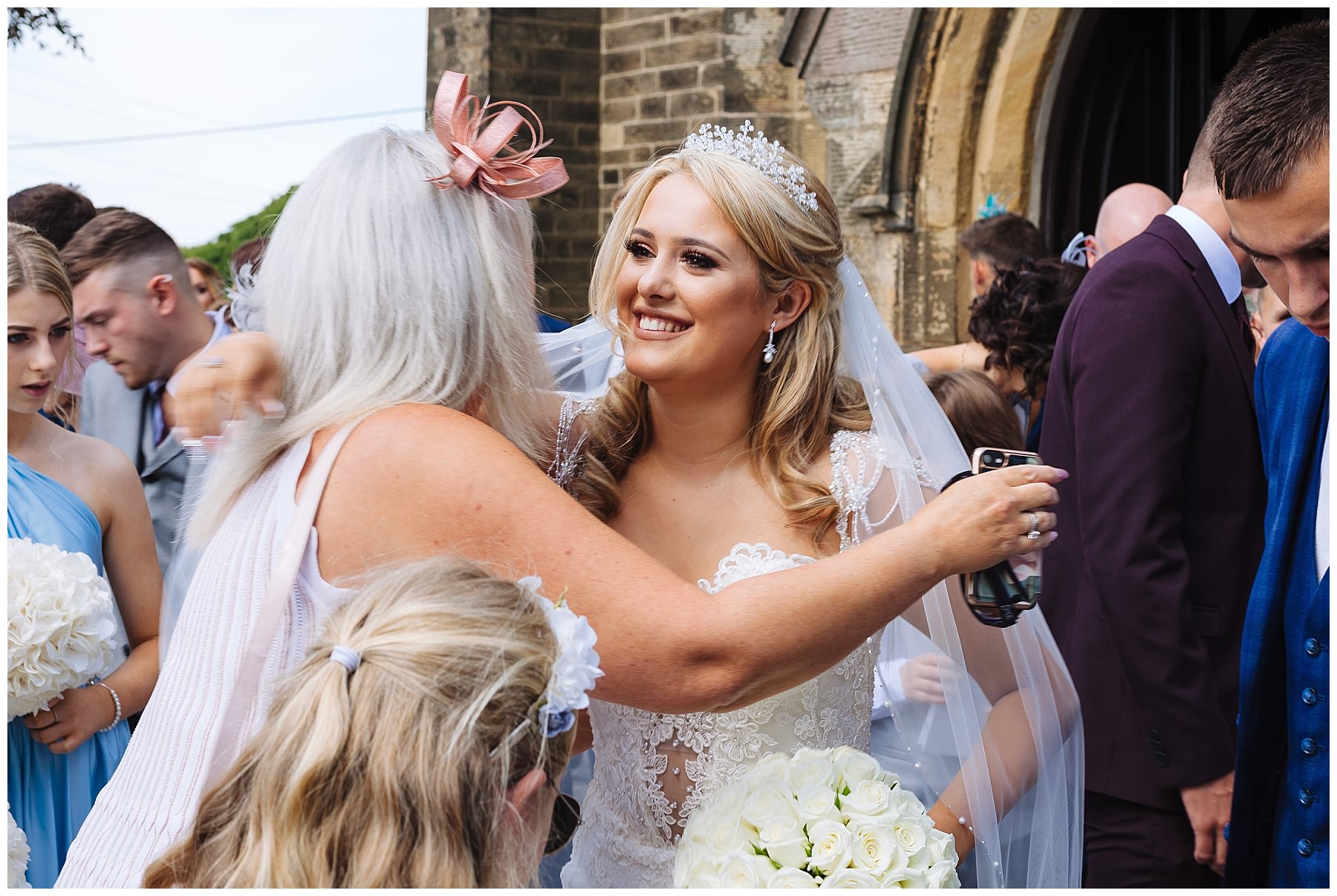 Bride smiles as she hugs guest after Lancashire Church Wedding
