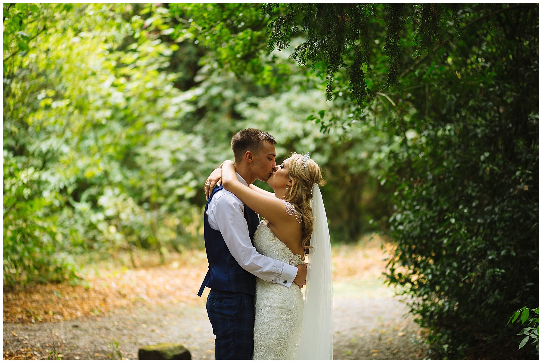married couple kiss under trees at Bartle Hall