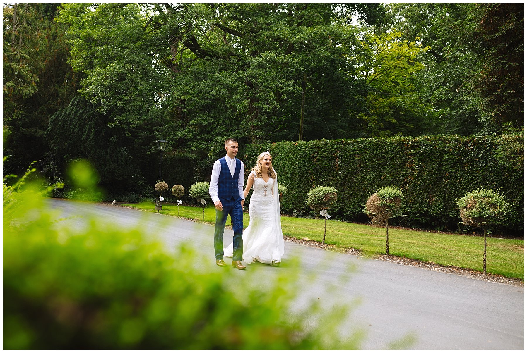 Wedding couple stroll through the gardens at bartle hall