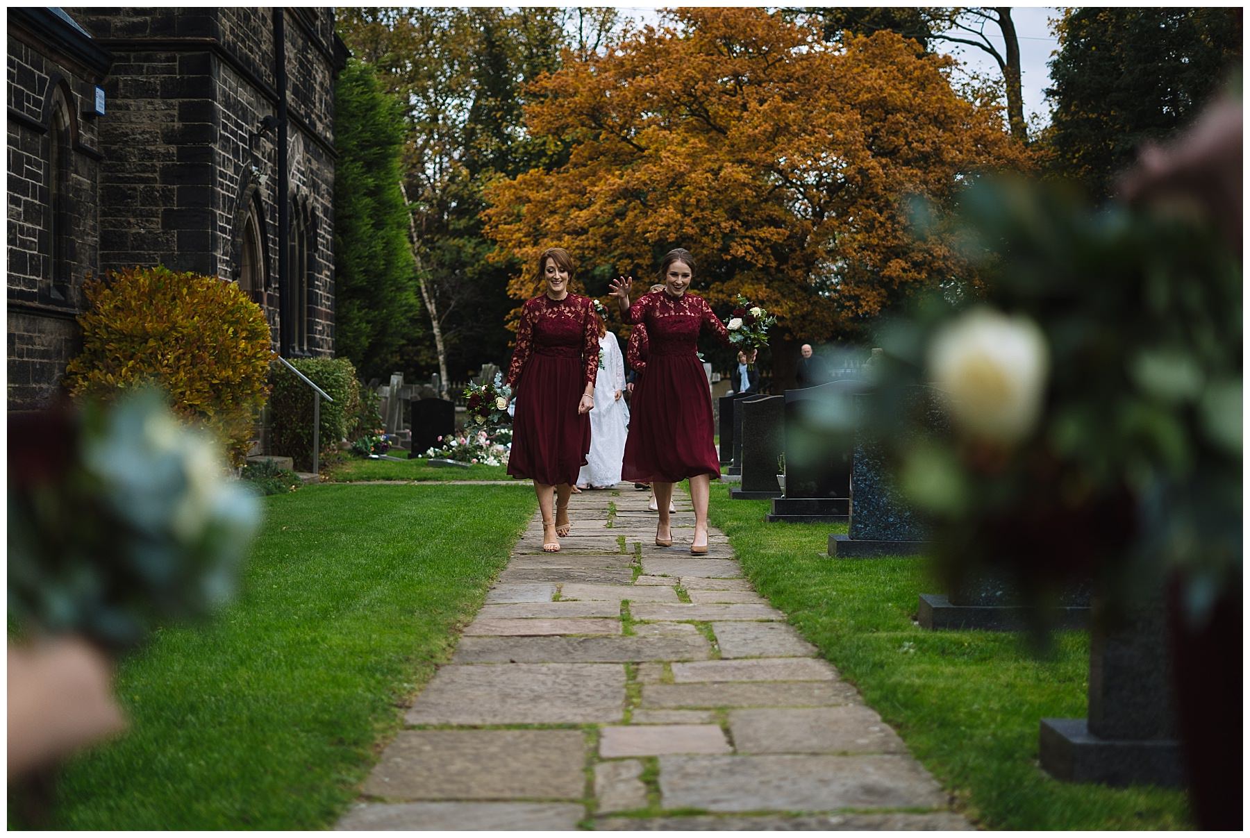bridesmaids walk towards church in burgundy dresses