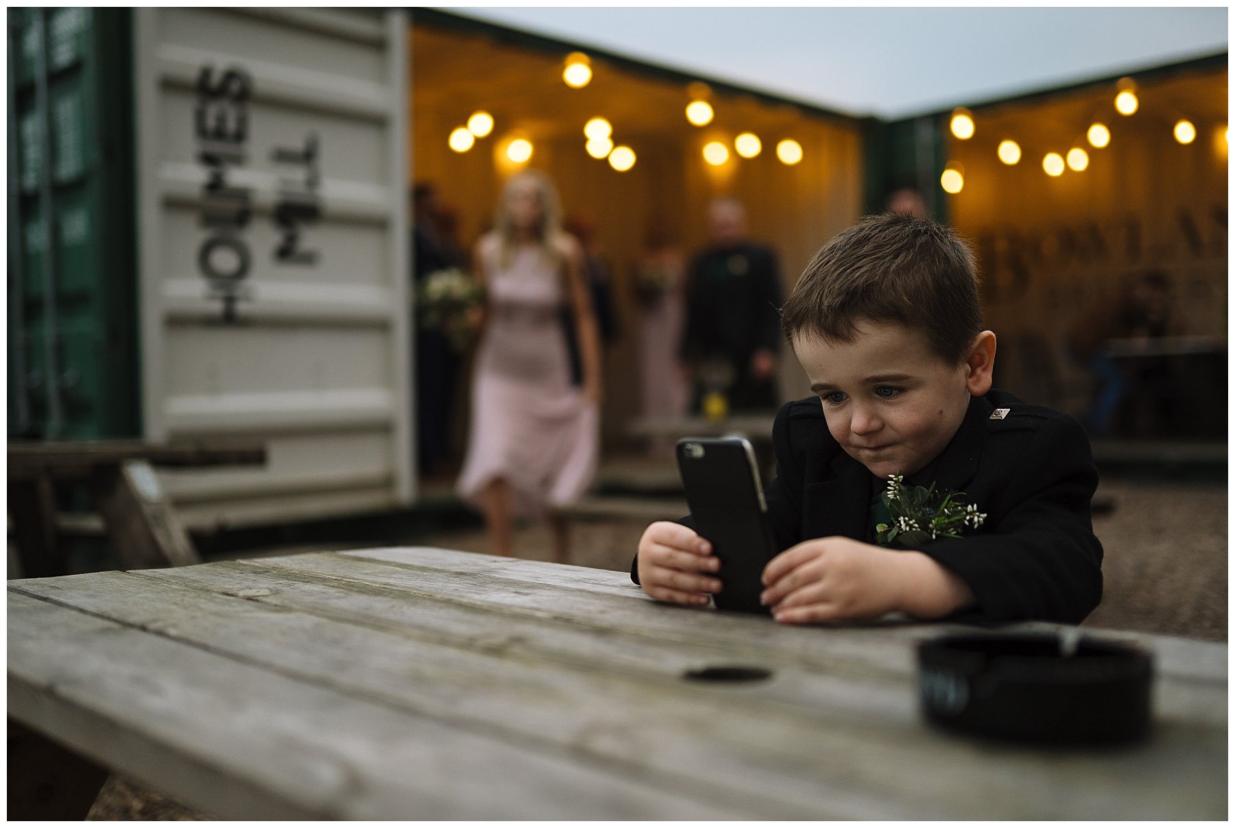 Page boy playing on phone during wedding