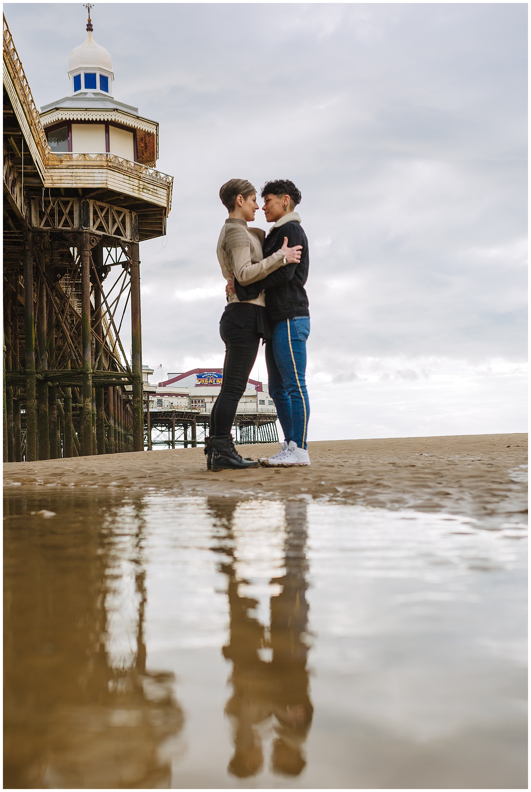 Couple reflected in standing water on Blackpool Beach