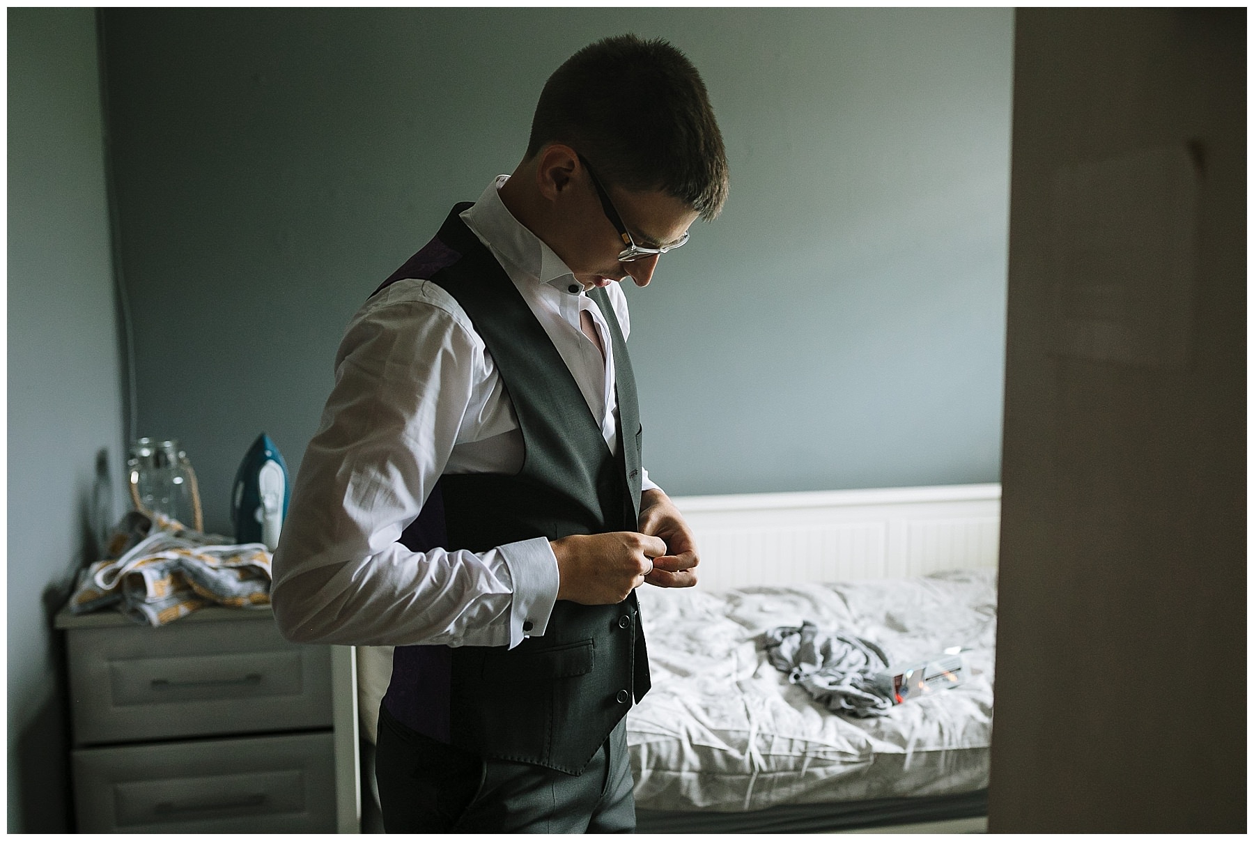 Groom fastens buttons on his waistcoat