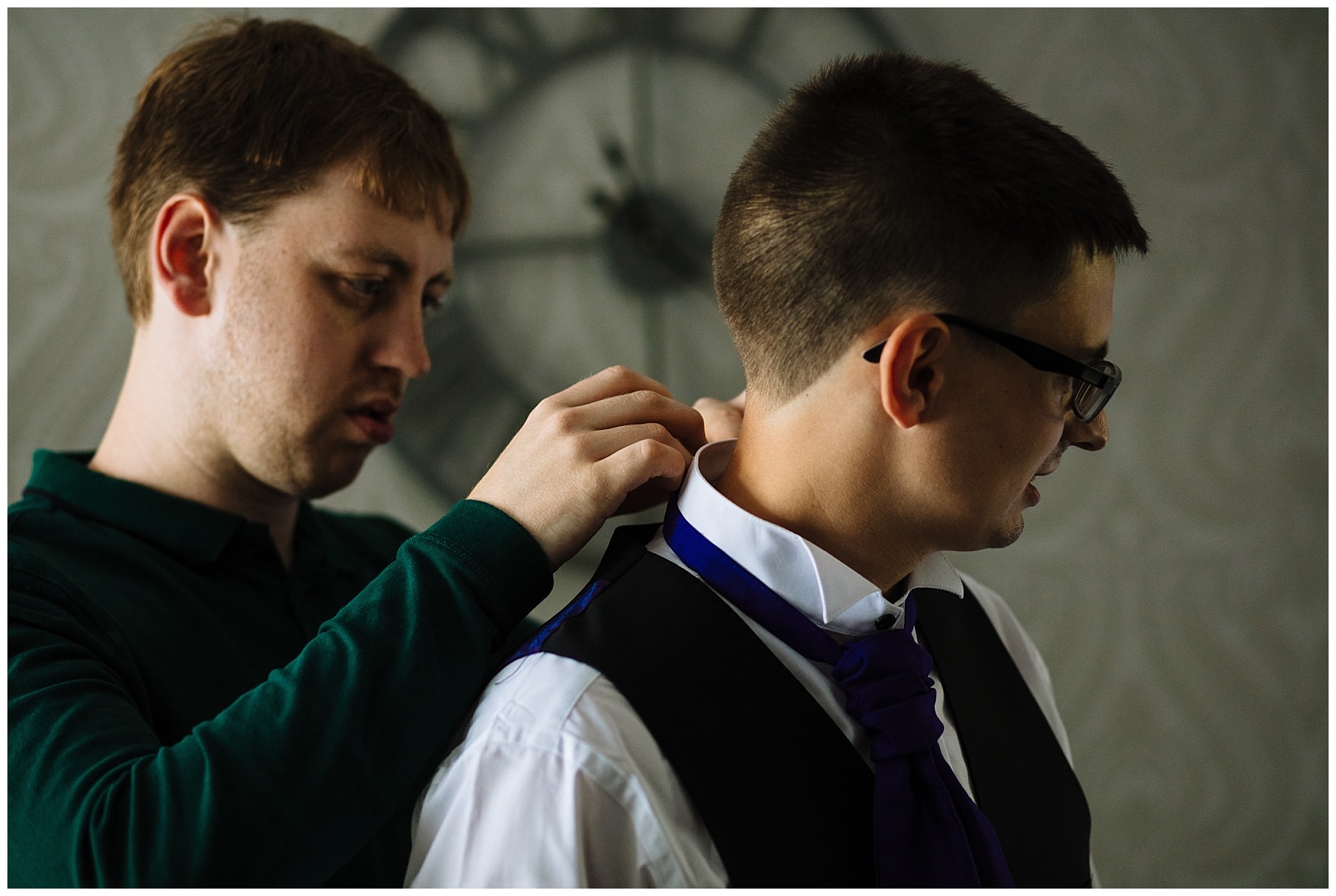 groomsman helps groom with his cravat