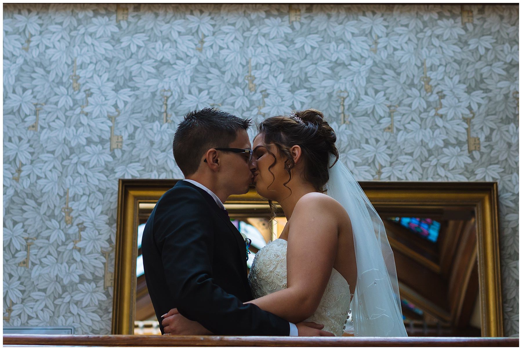 newly wed couple kiss on the stairs at Kilhey Court