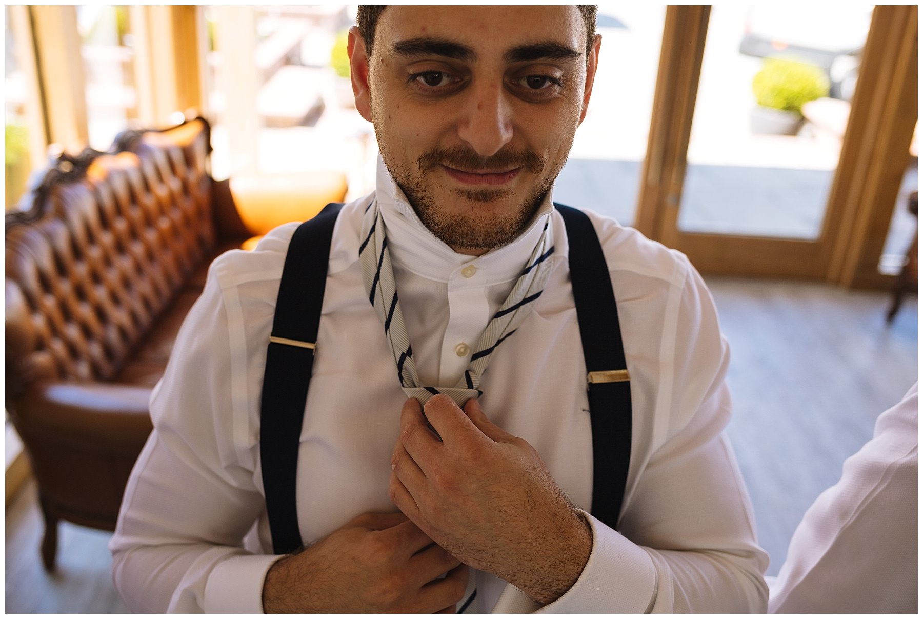 Groom puts on tie ahead of wedding