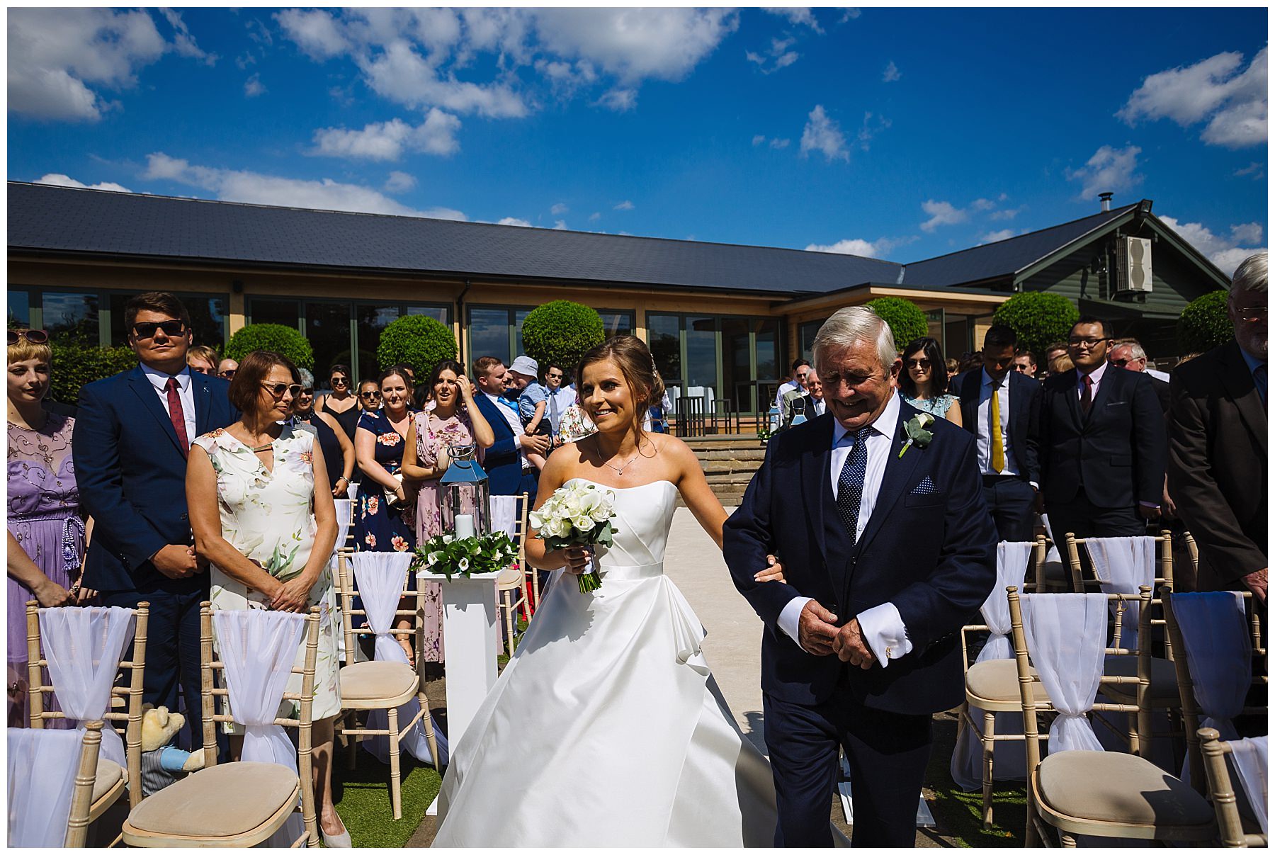 Bride is escorted by dad for outdoor summer ceremony