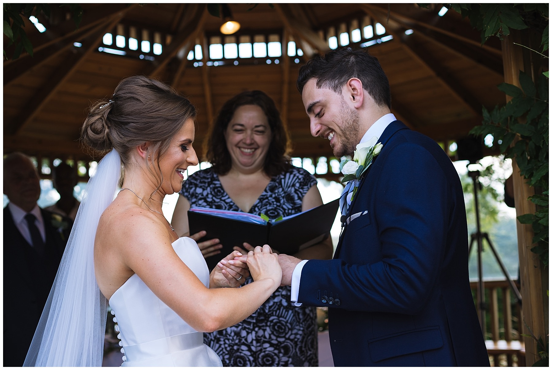 Bride and groom exchange rings during outdoor summer ceremony