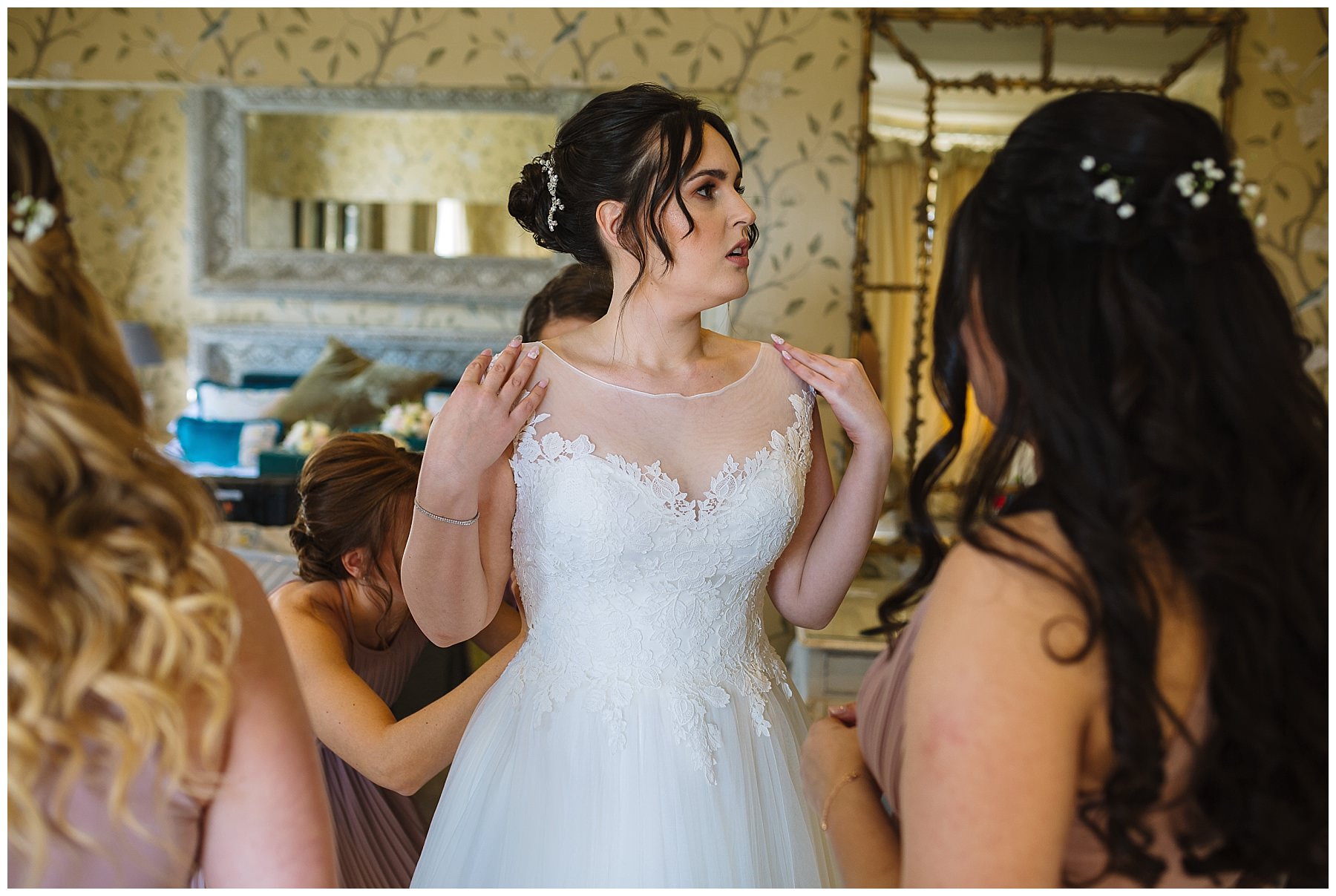 Bridesmaids help bride get into her dress