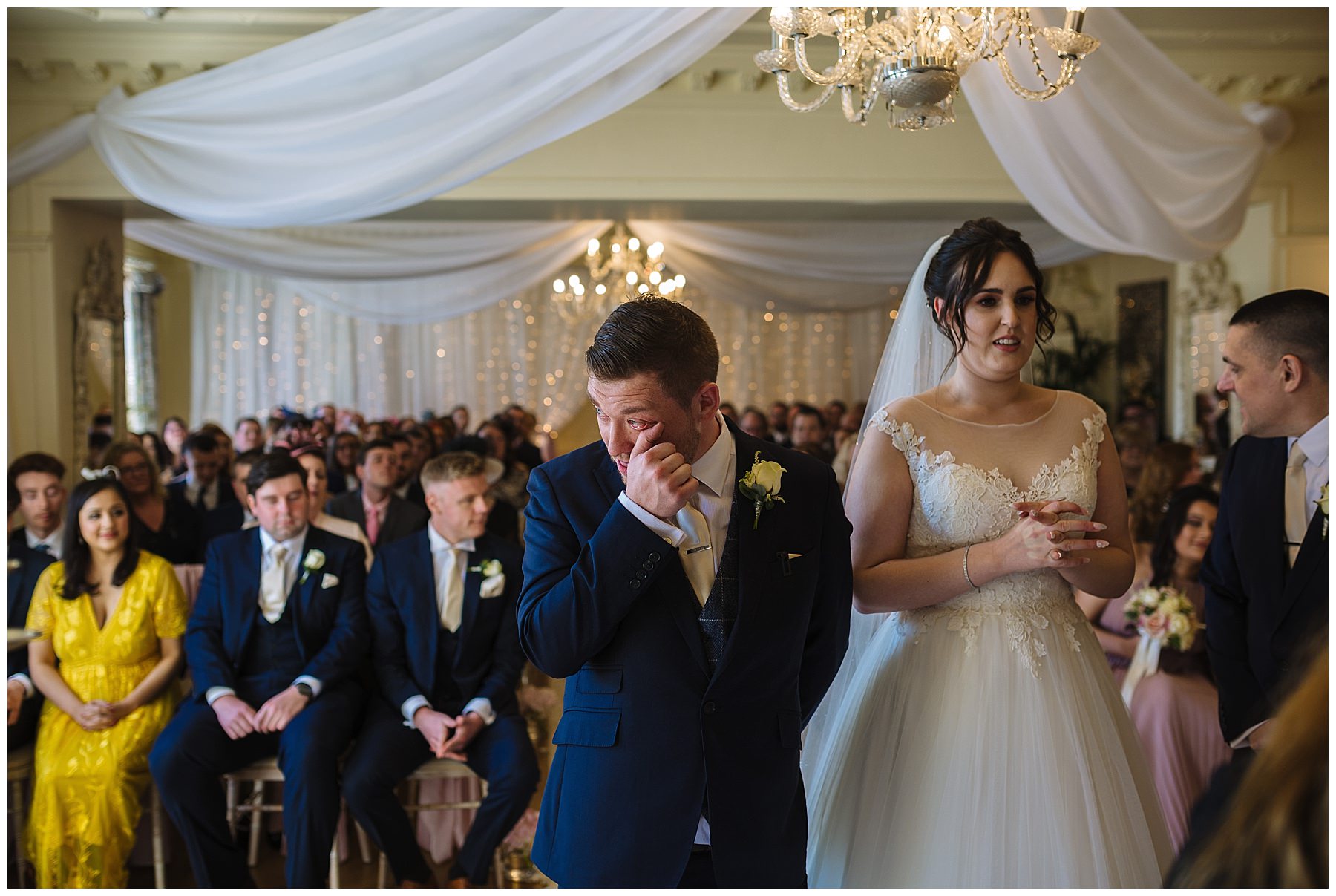 groom wipes away a tear during eaves hall wedding ceremony