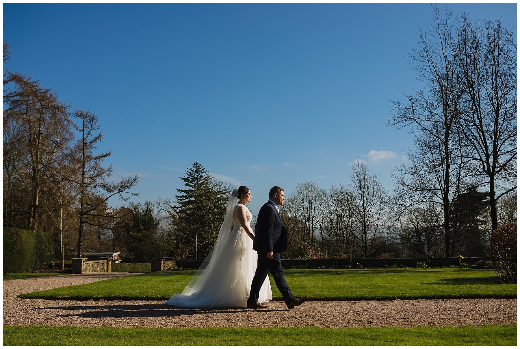 bride and groom walk through the gardens at eaves hall
