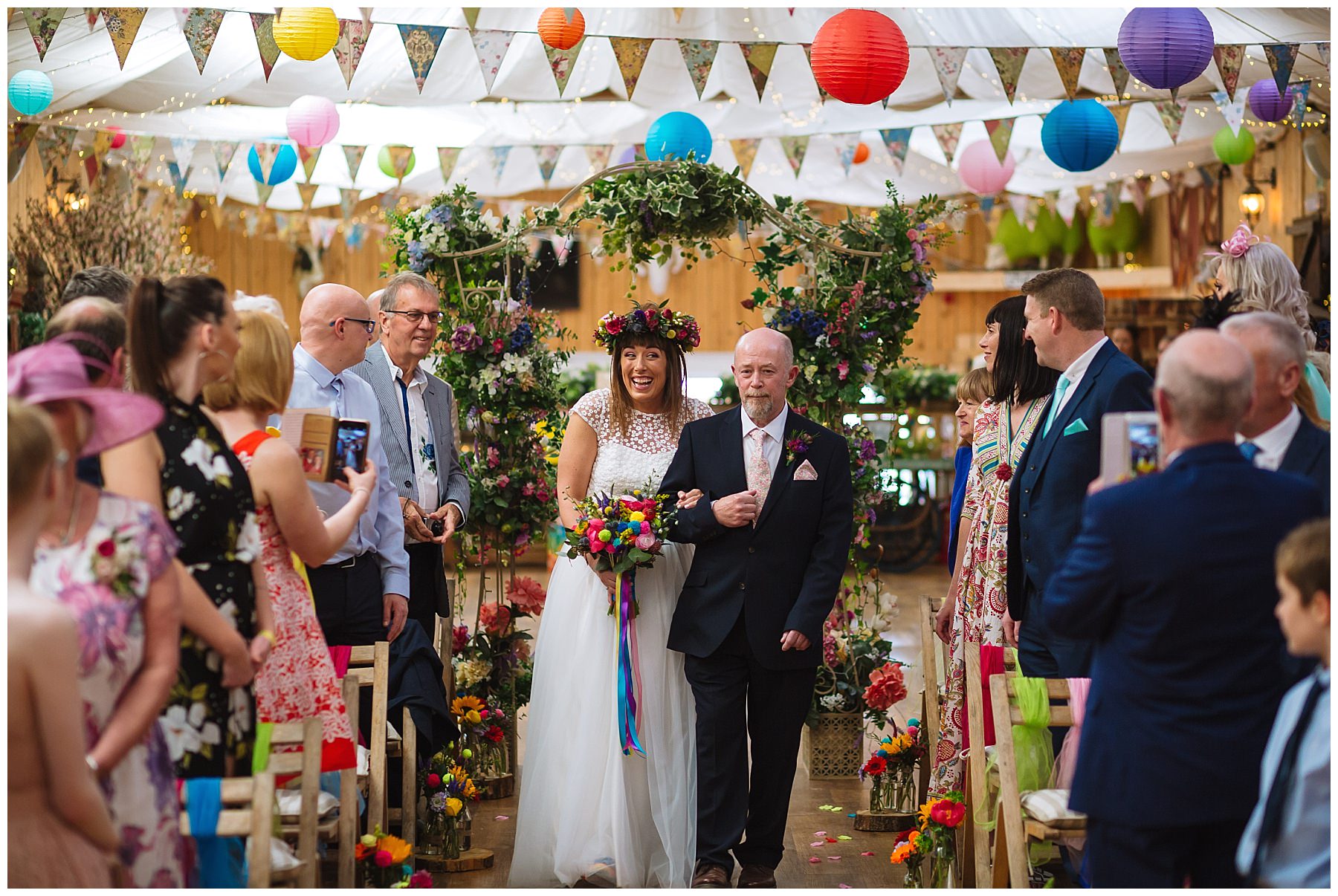 bride walks down the isle at the wellbeing farm arm in arm with dad