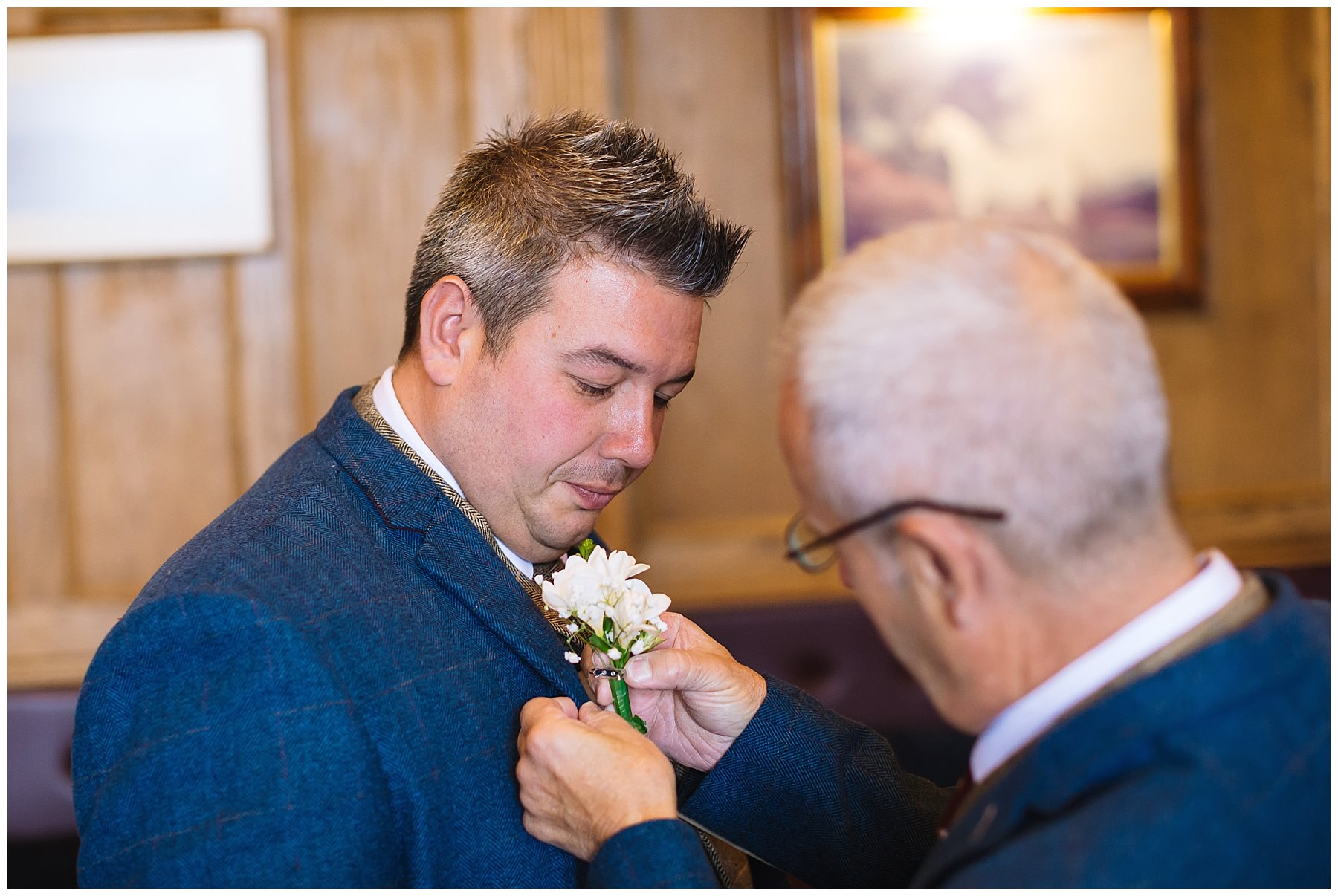 groom has buttonhole fixed by groomsman