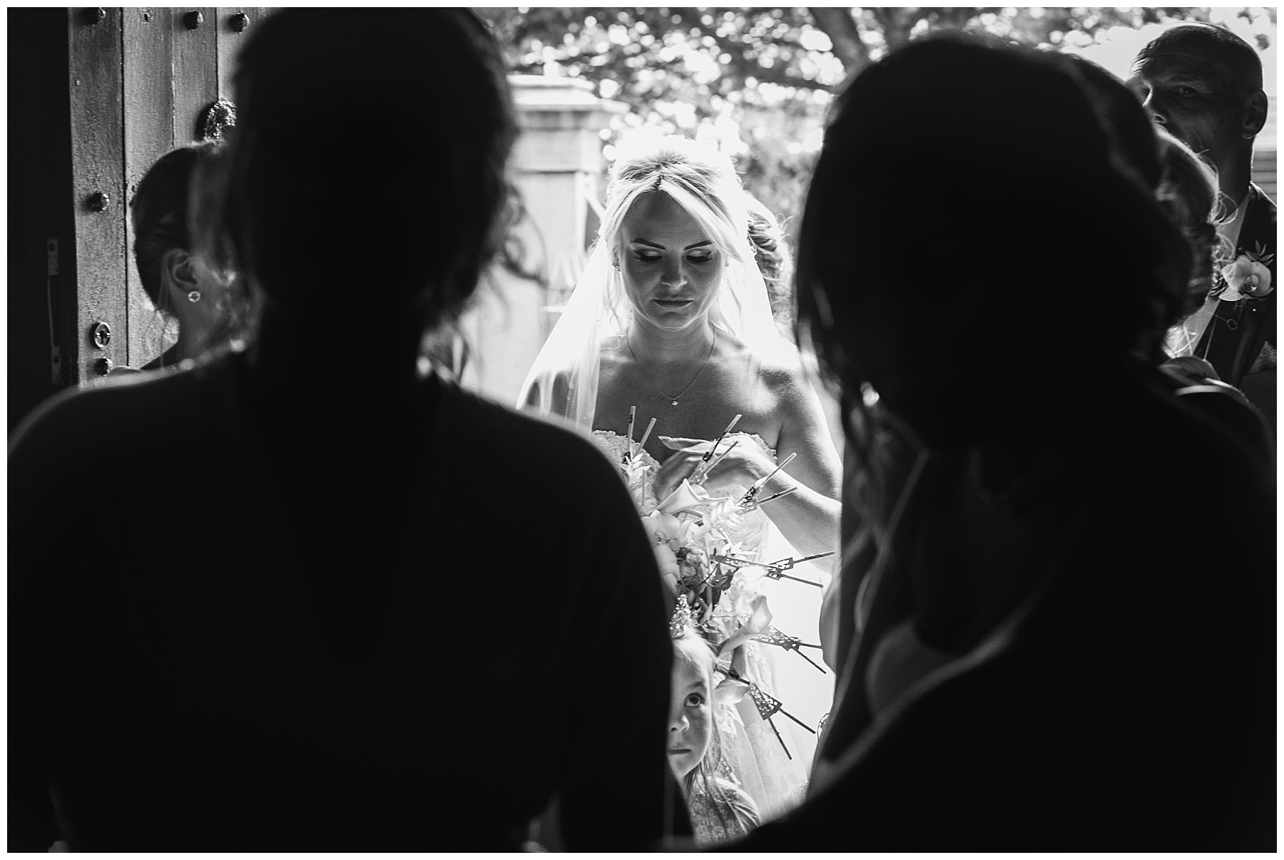 bride in black and white making finishing touches in church doorway