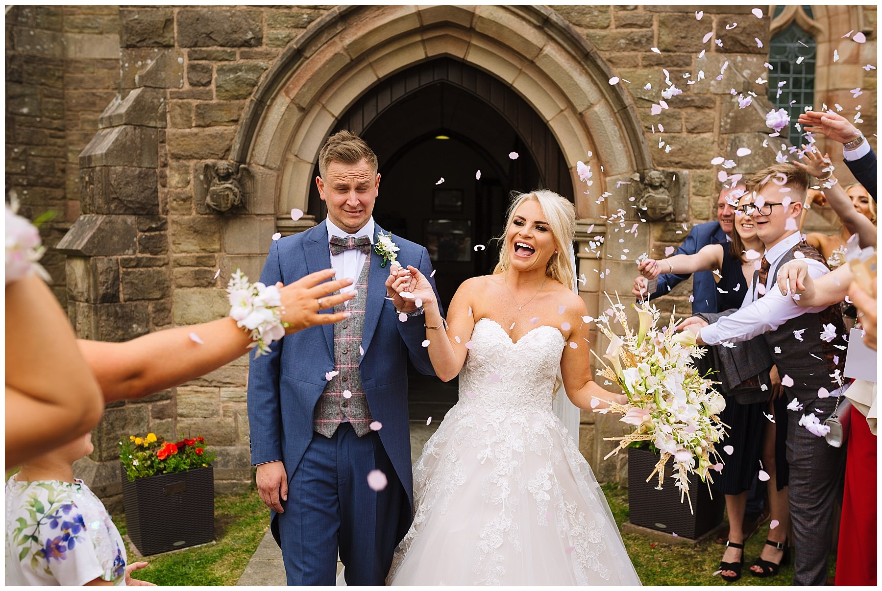 bride and groom laugh as they exit church to a shower of confetti