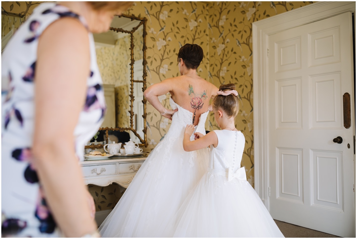 Brides daughter assists with wedding dress at eaves hall