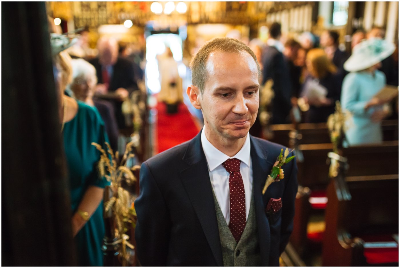 groom stands at the front of church waiting for his bride