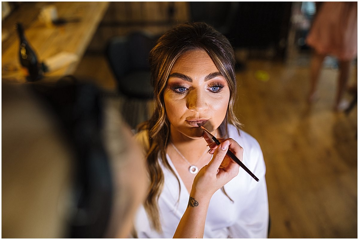 Makeup artist applies finishing touches to a bride at stock farm