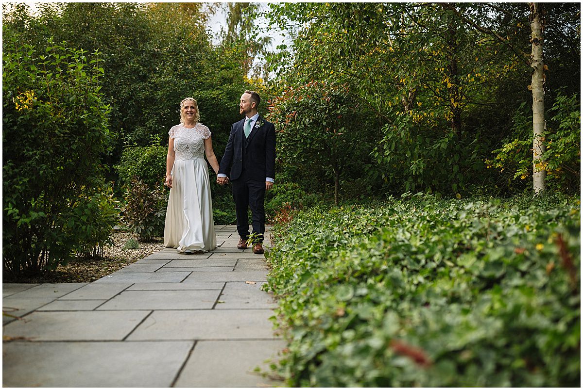 bride and groom take a walk through the gardens at styal lodge
