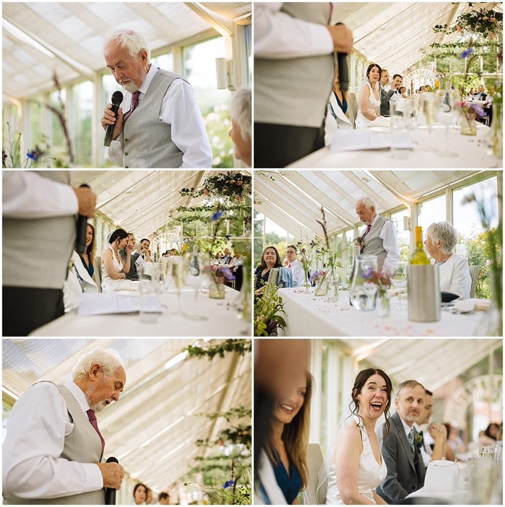 A heartfelt moment during a wedding reception as a speaker addresses the guests, while the audience, including the bride, shares smiles and laughter in a beautifully decorated venue.